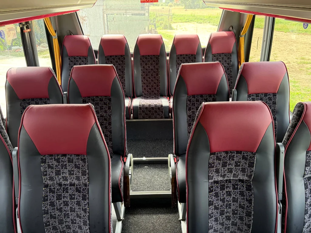Interno del minibus con sedili bordeaux e neri, vista frontale
